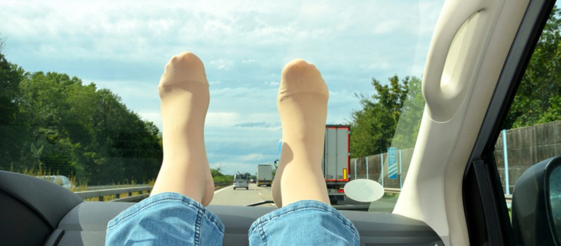Legs in compression stockings rest on the car’s torpedo. Concept for prevention of varicose veins and deep vein thrombosis during long journeys. Legs in compression stockings rest on the car's torpedo. Concept for prevention of varicose veins and deep vein thrombosis during long journeys.